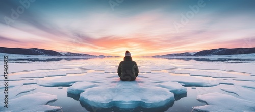 A person is standing on an ice floe with a sunset in the background. They appear calm and contemplative as they take in the serene natural beauty of the scene.