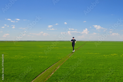 広い草原をジョギングをする男性