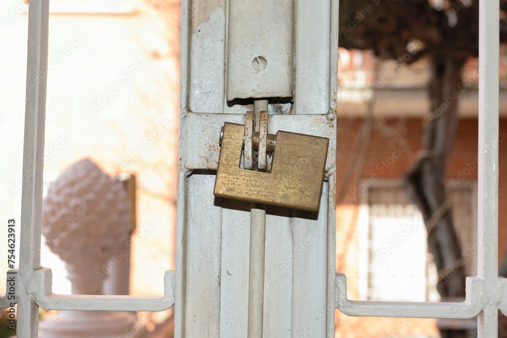 A metal square lock hangs on a metal old grill on the window - apartment security A metal square lock hangs on a metal old grill on the window - apartment security