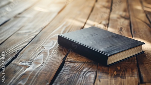 A black hardcover book closed on a rustic wooden table photo