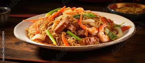 A plate filled with Pancit Canton noodles stir-fried with savory meat and colorful vegetables, creating a delicious and satisfying meal. The dish symbolizes longevity and is commonly served during