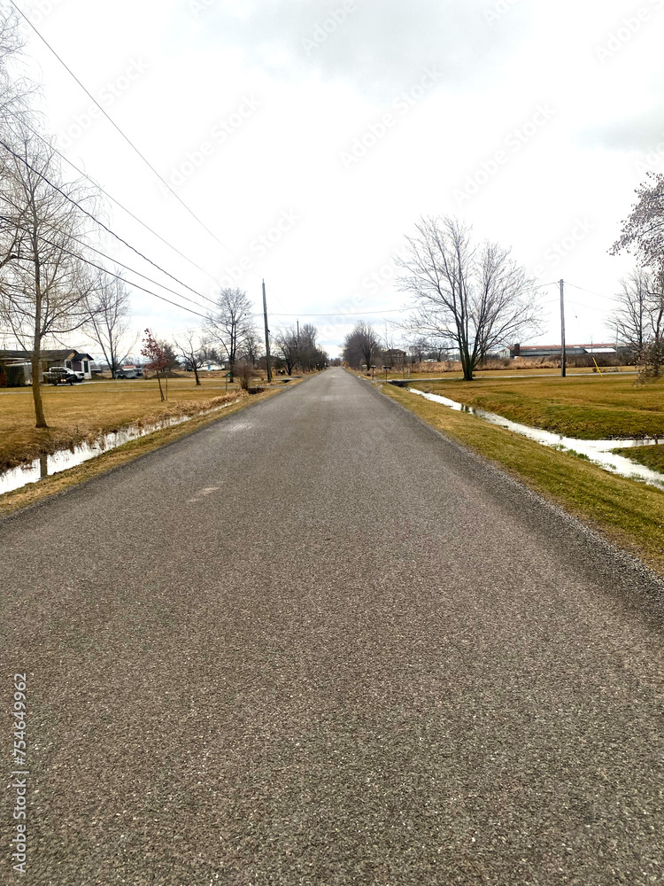 Stark rural road through farmland during spring tim