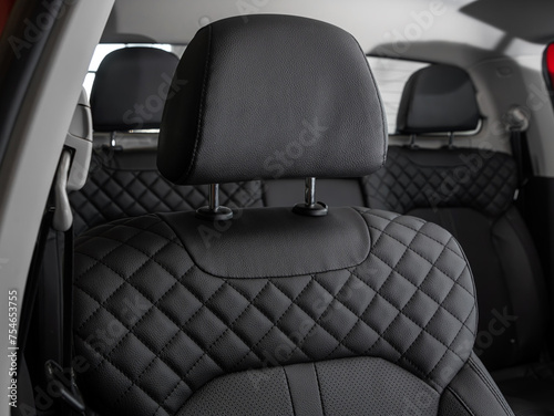  Close-up  leather black  rear seat made of  in the background passenger seats with seat belts. Luxury car interior © Виталий Сова