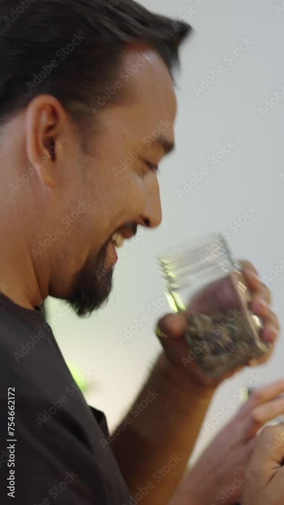 A man with a goatee sniffs a pot of weed A man with a goatee sniffs a pot of weed