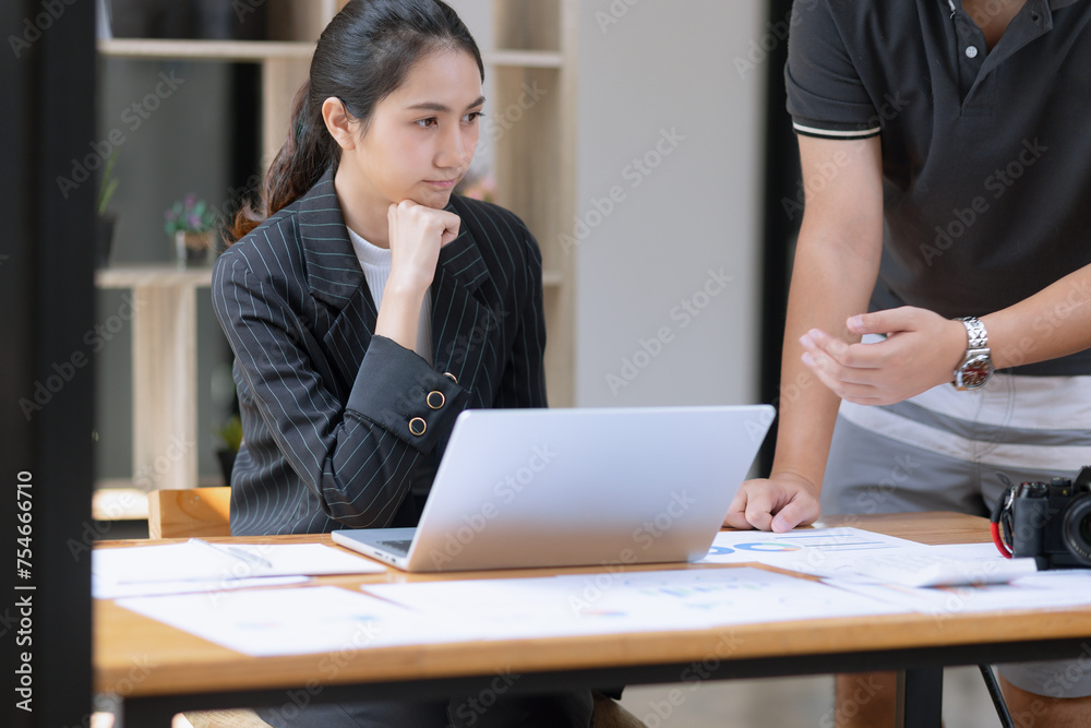 Photo of two business people using laptop computer and working together in the office desk. Photo of two business people using laptop computer and working together in the office desk.