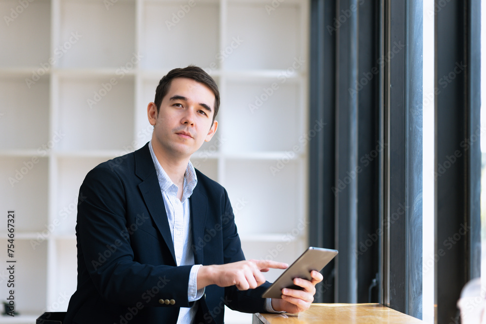 Businessman using tablet sitting at desk in office. Businessman using tablet sitting at desk in office.