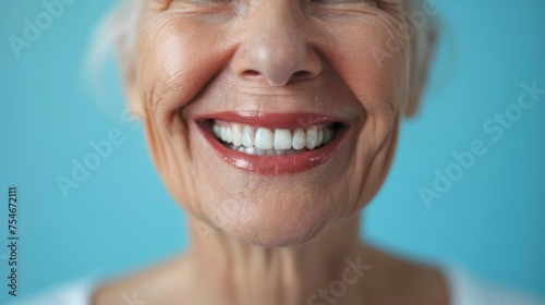 A close-up of a cheerful woman with natural teeth and a bright smile, exuding warmth, happiness, and positive aging, against a calm turquoise background.