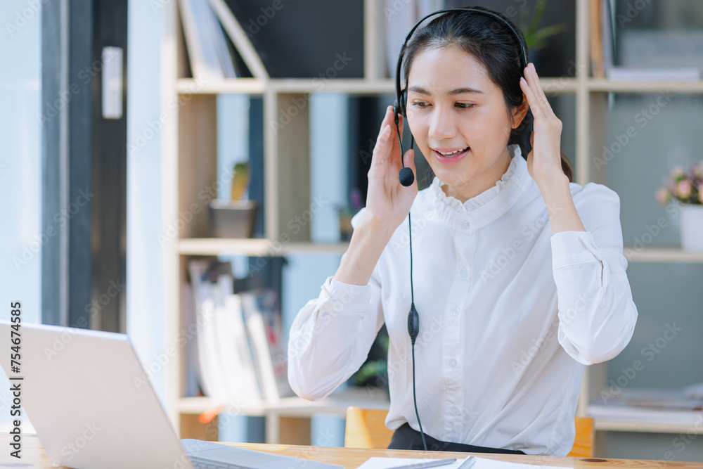 Asian businesswoman using laptop with earphones and working at desk in the office. Asian businesswoman using laptop with earphones and working at desk in the office.
