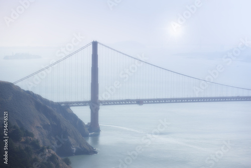 Golden Gate bridge, fog and ocean at sunrise by road, infrastructure or architecture in nature. Street, highway and hill with rocks, sea or horizon in morning sunshine for transport in San Francisco