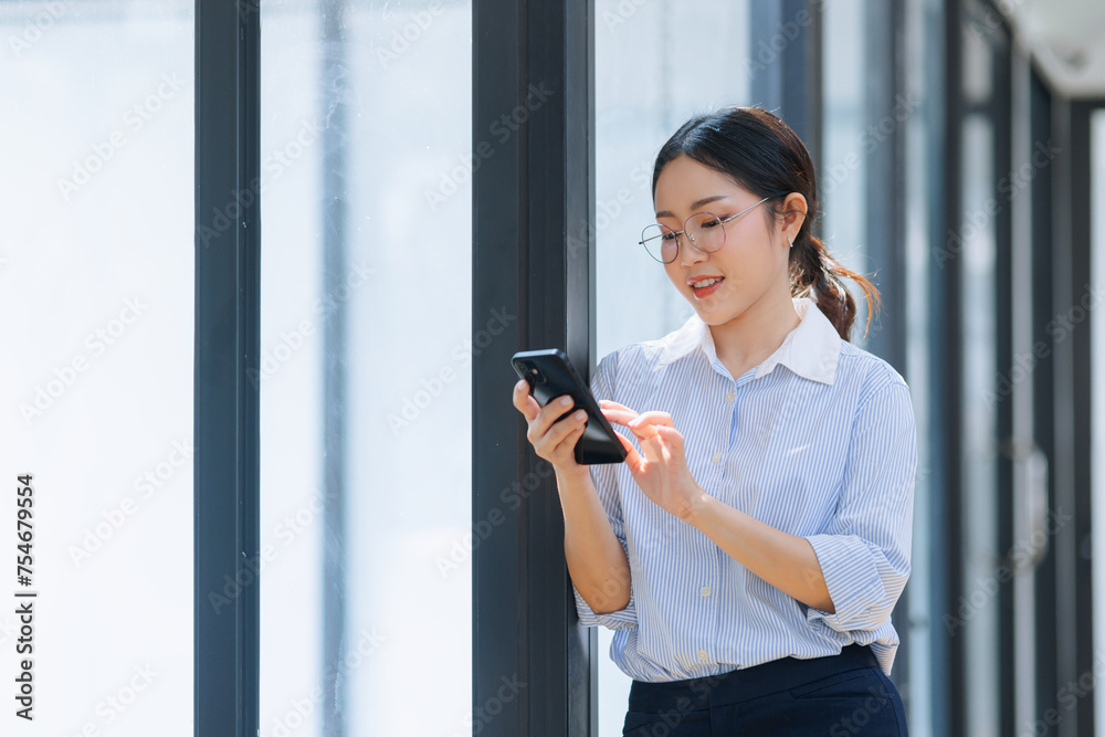 Asian businesswoman using smartphone standing at the office. Asian businesswoman using smartphone standing at the office.