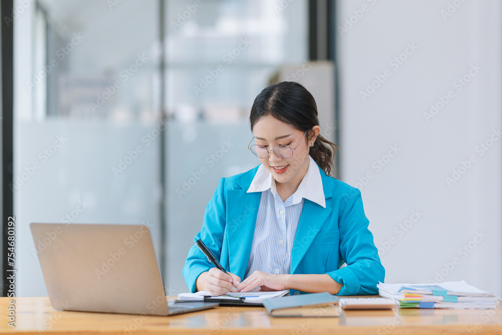 Asian businesswoman wear glasses with Wear a suit working on digital laptop computer in office. Asian businesswoman wear glasses with Wear a suit working on digital laptop computer in office.