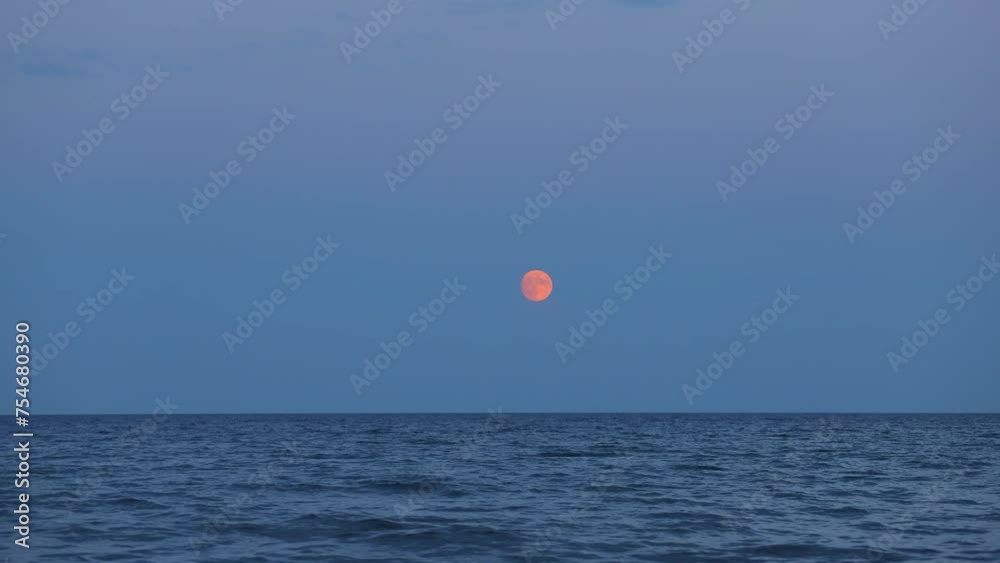 A full bright moon rises in the clouds sky over the water. Evening sky background. A natural phenomenon. Time-lapse A full bright moon rises in the clouds sky over the water. Evening sky background. A natural phenomenon. Time-lapse