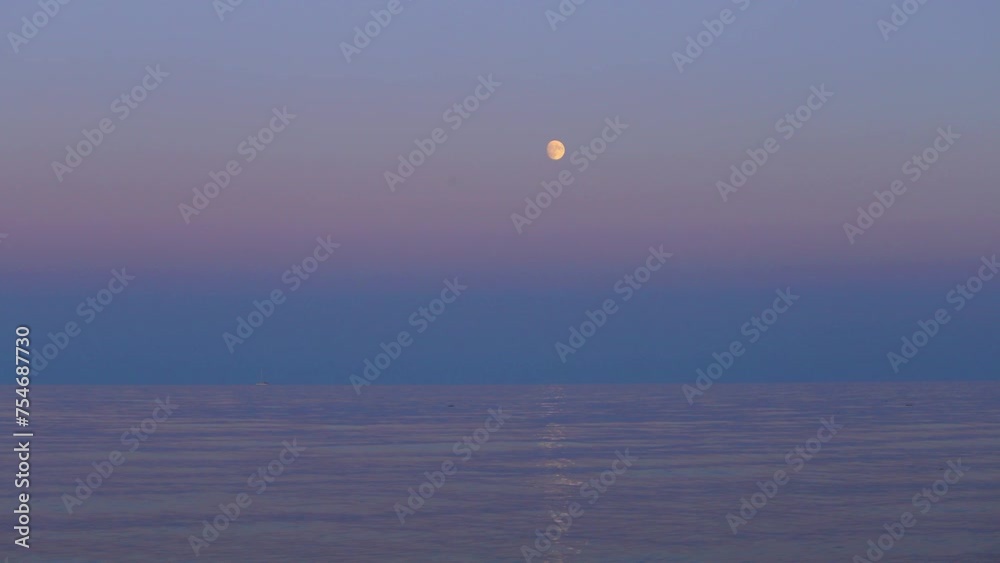 A full bright moon rises in the sky over the water. Evening sky background. A natural phenomenon. Time-lapse A full bright moon rises in the sky over the water. Evening sky background. A natural phenomenon. Time-lapse