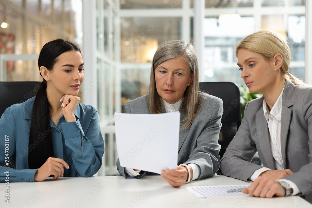 Lawyers working together with documents at table in office Lawyers working together with documents at table in office