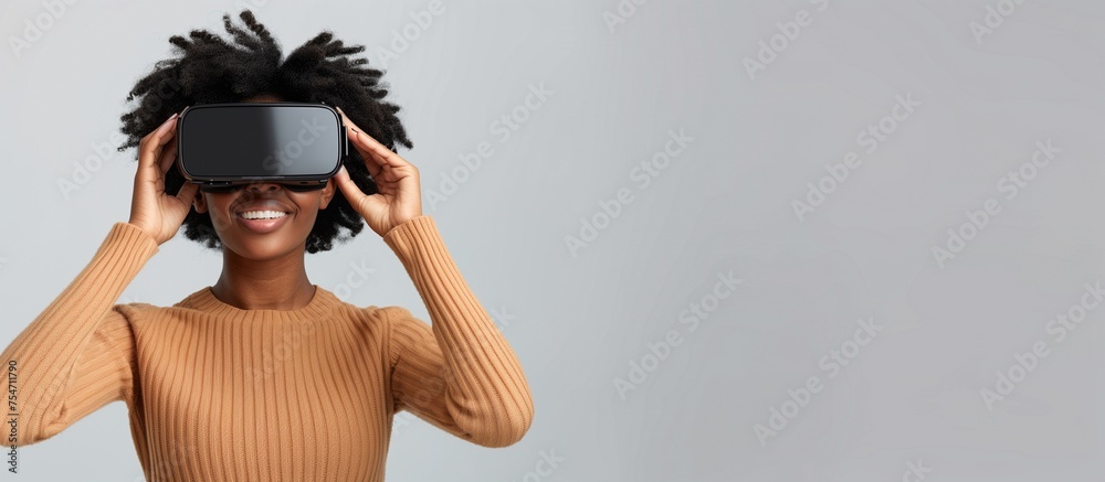 Excited and joyful Afro-American woman enjoying the wonders of virtual reality while wearing a VR headset. Black woman playing video games and discovering new worlds. Studio image, copy space Excited and joyful Afro-American woman enjoying the wonders of virtual reality while wearing a VR headset. Black woman playing video games and discovering new worlds. Studio image, copy space