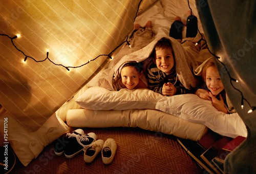 Children, smile and playing in blanket fort with portrait for fantasy, bonding and string lights at night. Friends, kids and face or happy for pajama party, sleepover and pillow tent with lighting