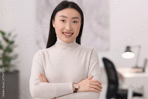 Portrait of smiling businesswoman with crossed arms in office