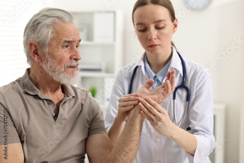 Arthritis symptoms. Doctor examining patient's hand in hospital