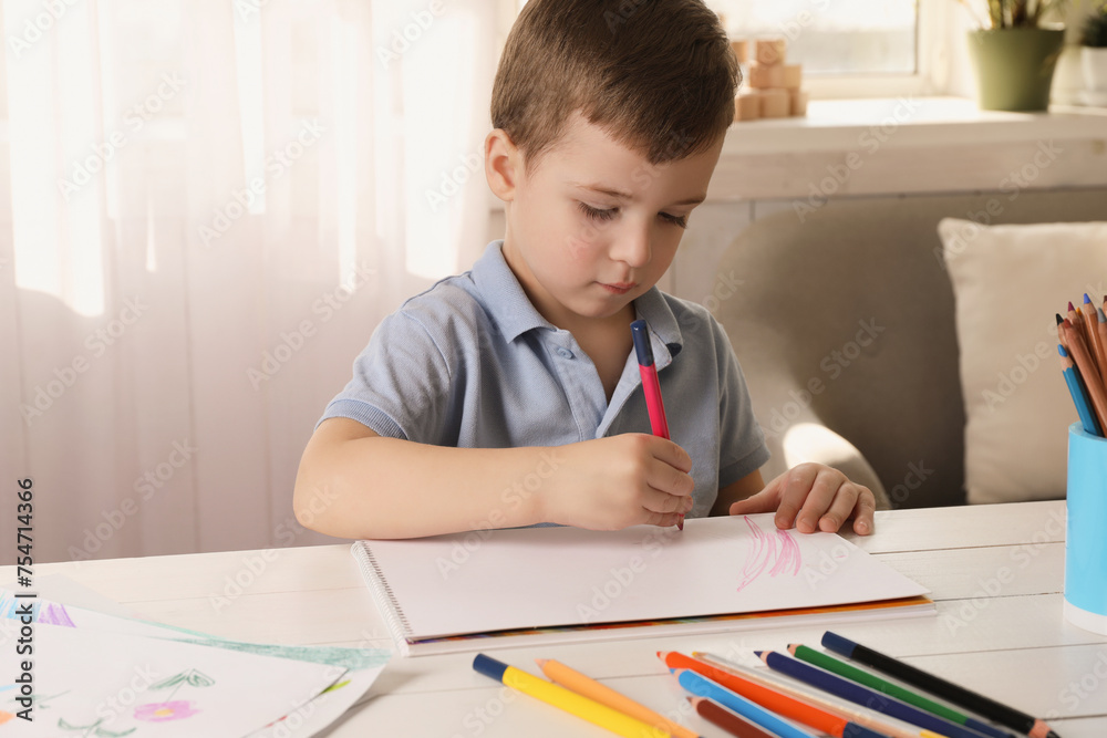 Cute little boy drawing with pencil at white wooden table in room. Child`s art Cute little boy drawing with pencil at white wooden table in room. Child`s art