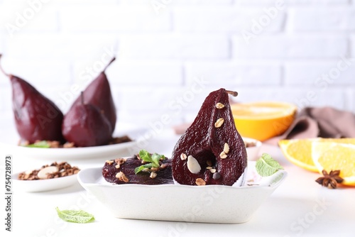 Tasty red wine poached pears with muesli and yoghurt in bowl on white table