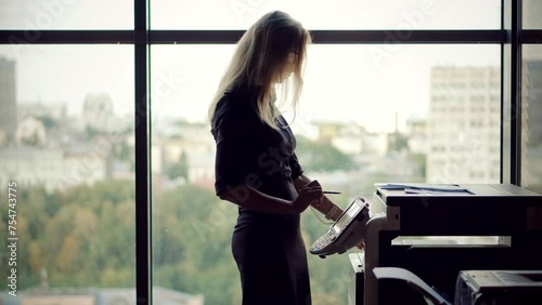 Businesswoman uses printer in office to replicate paperwork