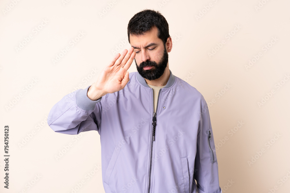 Caucasian man with beard wearing a jacket over isolated background making stop gesture and disappointed Caucasian man with beard wearing a jacket over isolated background making stop gesture and disappointed