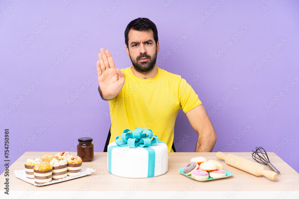 Man in a table with a big cake making stop gesture Man in a table with a big cake making stop gesture