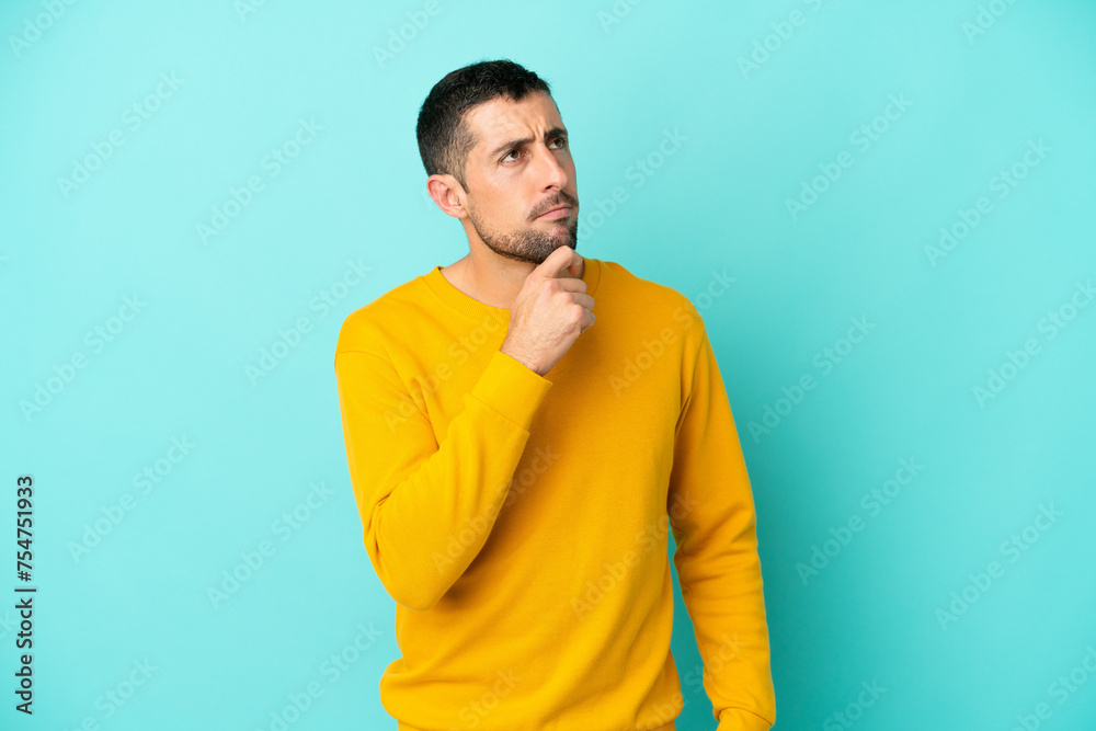 Young handsome caucasian man isolated on blue background and looking up Young handsome caucasian man isolated on blue background and looking up