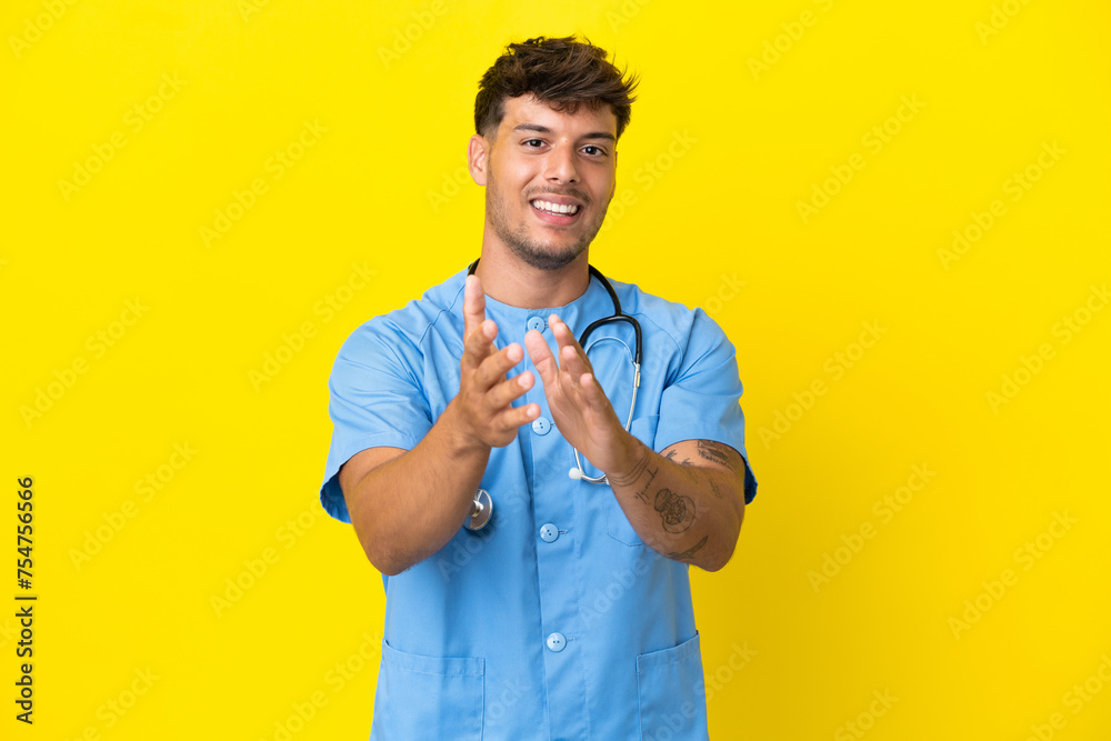 Young surgeon doctor man isolated on yellow background applauding after presentation in a conference Young surgeon doctor man isolated on yellow background applauding after presentation in a conference