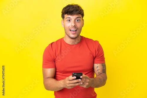 Young caucasian handsome man isolated on yellow background surprised and sending a message © luismolinero