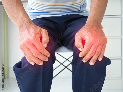 Man suffering from knee pain sitting chair at home, bone and joint diseases. Medical concept.