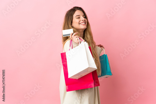 Young woman with shopping bag isolated on pink background holding shopping bags and a credit card