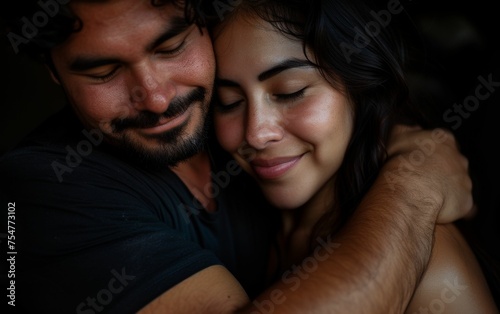 A multiracial man and woman are wrapped in a warm embrace, showing affection and closeness