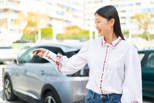 Young Chinese woman at outdoors holding car keys photo