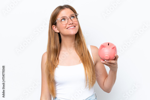 Young pretty blonde woman holding piggy bank isolated on white background looking up while smiling