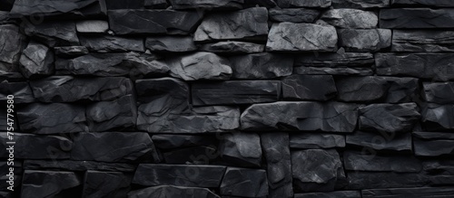 A close-up black and white photograph showcasing the intricate patterns and textures of a stone wall. The contrast between dark and light areas creates a visually striking abstract composition.