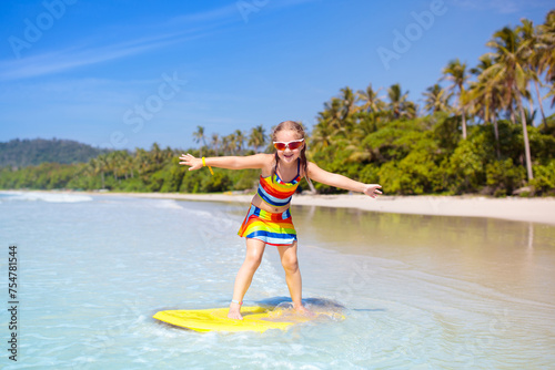 Photography Child surfing on tropical beach. Surfer in ocean.