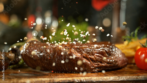 Close-up of falling salt on tasty beef steak in kitchen.