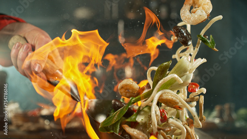Freeze motion of flying asian wok noodles with prans and vegetable. The concept of meat preparation.