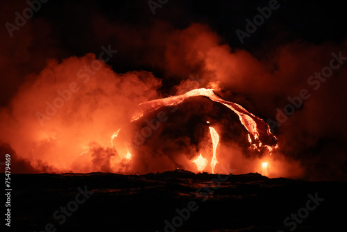 Red hot lava from the volcano in Hawaii frowing into the sea at night photo