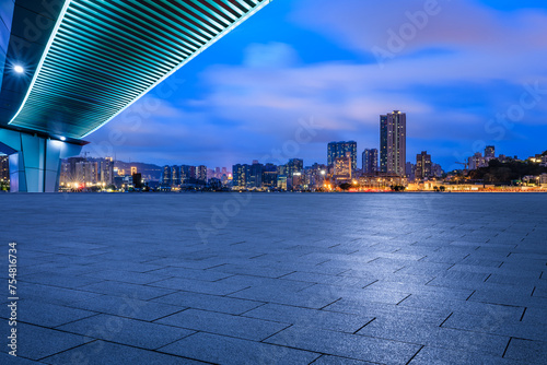 Empty square floor and pedestrian bridge with city buildings at night