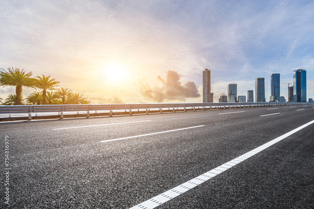 Asphalt highway road and city buildings at sunset