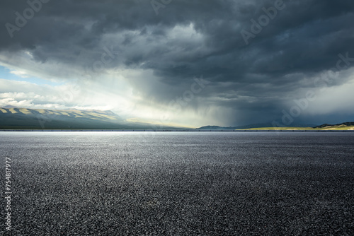 Fototapeta Naklejka Na Ścianę i Meble -  Asphalt road and mountains with dark clouds before heavy rain