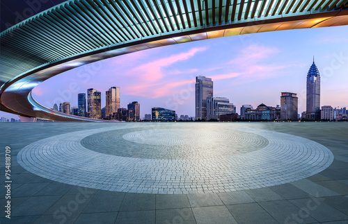 Round square floor and pedestrian bridge with modern city buildings at dusk in Shanghai
