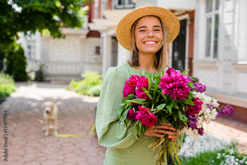 beautiful young woman in summer style outfit smiling happy walking with flowers in city street