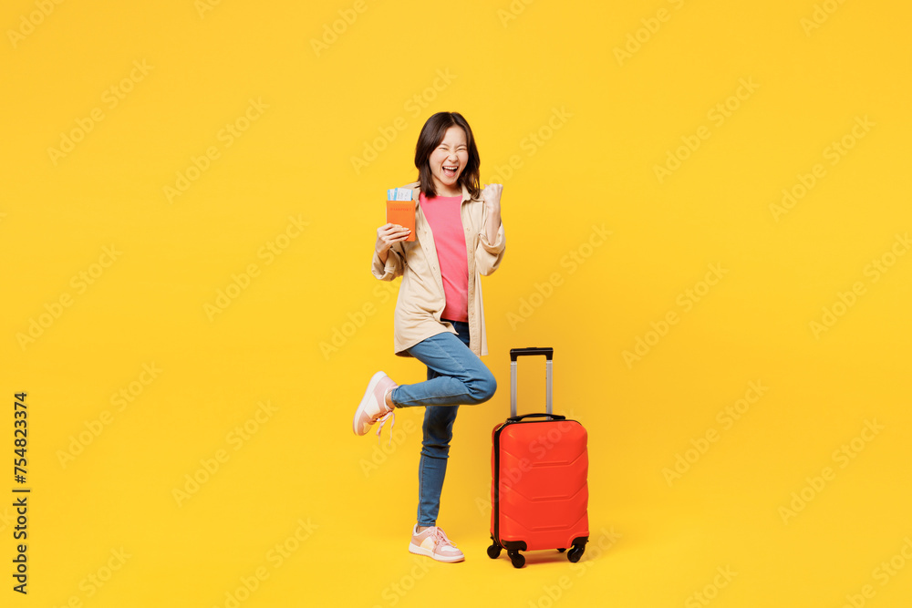 Traveler woman wear casual clothes hold passport ticket bag do winner gesture isolated on plain yellow background Tourist travel abroad in free spare time rest getaway Air flight trip journey concept