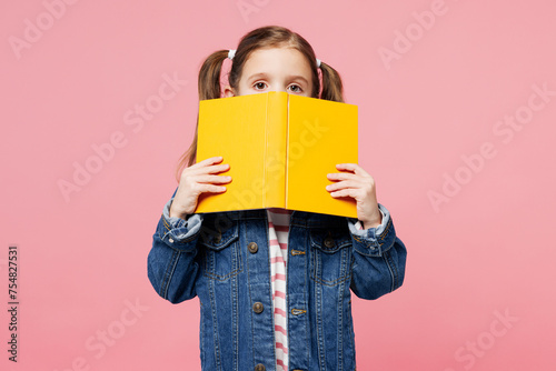 Little child cute kid girl 7-8 years old wears denim shirt have fun hold in hand read cover mouth with book isolated on plain pastel light pink background. Mother's Day love family lifestyle concept. photo