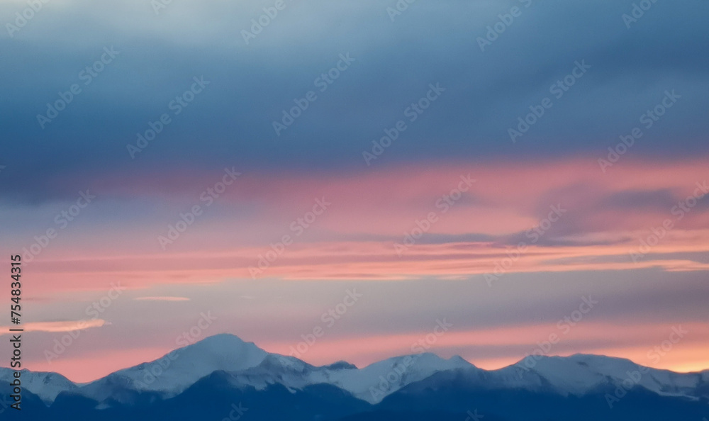Tramonto rosa e arancio sopra le cime dei monti innevate