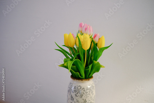 tulips in an old vintage vase against a white wall yellow and pink flowers in a vase on a table
