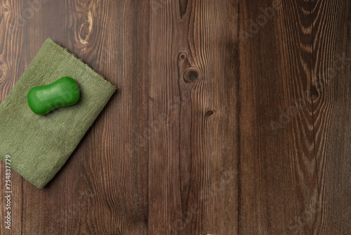 A piece of green soap on a towel on a wooden background. Spa concept